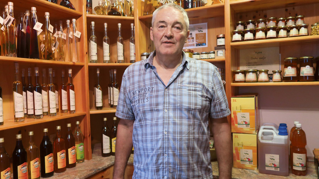 Ivo Turk v prodajalnici na svoji kmetiji s številnimi izdelki iz sadja in medu. 